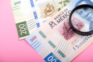 Paper currency of Mexico and magnifier on pink background, mexican pesos